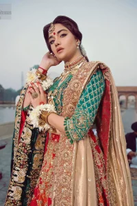 Classic, timeless and truly beautiful, our bridal dress is perfect for your unforgettable day. Excellence of craftsmanship is evident with intricate detailing that features the use of zardozi work. The blouse is beautifully adorned with geometric patterns and floral embroidery with golden zardozi work and finished with dangling beads. Complete the look with artfully coordinated lehenga which is ornamented with a bold and captivating design with a traditional intricate embroidery and scattered tiny floral motifs. The combination of red and orange for lehenga is also captivating. Elegance is personified when it gets paired up with golden dupatta having four sided embroidered border.