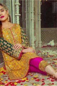 Embrace the season of festivities with this beautiful dress. This beautiful mehndi dress comes with a pink capri pants with beautiful embellished applique around the bottom and the shirt is designed with vertically worked gold lines and it finished with a thick appliqued embellished border. The shirt looks more whimsical when it comes with embellished green sleeves with golden zardozi work. Balance the look with yellow organza dupatta scattered with sequins on the ground.