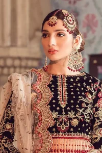 The new season is all about making a statement. Captured in traditional silhouette, The bridal stands out due to its uniqueness and the perfect fusion of modern cut and traditional embroidery. Black velvet blouse is beautifully decorated with multiple colour embroidery and finished with tassels. It comes with full embellished velvet lehenga adorned with applique all around the edges and motifs all over it. This outfit is coordinated with beige net dupatta which is sprinkled with sequins all over it. It is further furnished with a four-sided scalloped border.