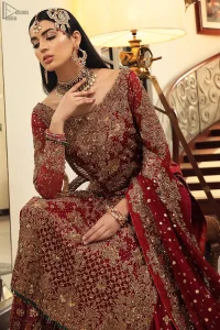 Maroon bridal wear long shirt, appliqued Gharara and matching heavily embroidered dupatta. We will make you believe in fairy-tales! Ethereal handcrafted luxe ensemble, fit for a princess glammed out with gorgeous layers of hand-embroidered details, timeless silhouette and dreamy embellishment. The outfit is finished with beautiful maroon organza gharara having appliqued embroidery below the gott. This colourful gharara having thick embroidery borders gives it a regal look.