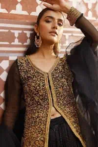 With the timeless charm of black so back on traditional flavour to steal everyone's heart. Introducing the black jacket that is the epitome of splendour with delicate details beautifully decorated with golden colour. The bodice of the jacket is enhanced with stunning embroidery with worked finishing of tilla, kora, dabka and zardozi. The addition of simple sleeves with V shape neckline can be done to make this super traditional. To complete this traditional jacket, a crushed sharara is added to give you an amazing look at any formal event. Complete this black outfit with a black dupatta in a plain style that is perfect for any intimate evening