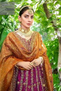 The outfit defines the true essence of allure with its spellbinding magenta hue and intricate details. The blouse is decorated with golden embroidery based on the neckline and sleeves. The sleeves are further enhanced with the embellished handwork. It is Beautifully organized with a magenta lehenga that is again heavily embellished with golden embroidery that is just adding poise to the whole look. Paired along with an orange dupatta decorated with subtly adorned motifs and embellished border that is completing this Mehandi looks wondrously.