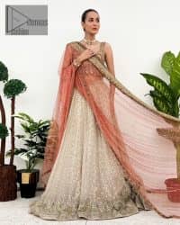 The perfect outfit for walima to enhance your glow. Starting this article with a dream rust blouse having a strap neckline and prominent sleeveless style to embrace the romantic culture. The following blouse is fully embellished with golden embroidery that is prominent with tilla, dabka, kora, pearls and sequins spray to fulfil your dreamy look. It is coordinated with an ivory can-can lehenga whose border is again rendered with golden embroidery and sequins sprayed all over to continue the look. Complete this outfit with a rust dupatta which is embellished with four-sided borders and sequins sprayed all over to enhance the glow of the bride.