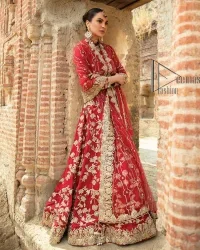 Begin your new life by wearing a romantic deep red outfit. Introducing this Pakistani reception wear that begins with a handsome blouse which is adorned with tiny floral motifs all over in light golden colour. The boat shape neckline steals the spotlight of the event when comes with three-quarter sleeves. It is combined with flared lehenga which is heavily adorned with a light golden embroidery to make your event lovely and charming. Complete this Pakistani reception wear with a dupatta in the same colour which border is heavily embellished that is ideal for modern festives.