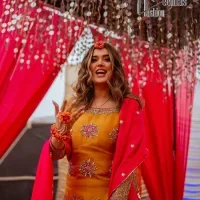 We seek outside the wonders we carry inside us. A mehndi dress in the mustard shirt is enhanced with gorgeous gota work. and is designed using the floral technique in pink and golden which is incrusted with tilla, dabka, kora and Sitara. The border of the mustard shirt is heavily ornamented with golden embroidery. The round neckline enhances the beauty of this mehndi dress when comes with three-quarter sleeves. It is paired up with mustard Gharara which is super simple and its border is encapsulated with Kiran. Complete this mehndi dress with a pink dupatta having ting floral motifs all over.