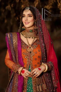 A colourful mehndi outfit is a power which directly influences the soul. Begin this mehndi outfit with a rusted front open shirt which is beautifully decorated with colourful embroidery to give you more power on your mehndi day. It is prominent with tilla, dabka, kora and zardozi. Further, the V shape neckline adds to this mehndi outfit when comes with full sleeves. Paired with a green lehenga having multiple colour borders to give you a more traditional look also. Complete this mehndi outfit with a colourful dupatta which is adorned with four-sided borders and sequins sprayed all over.