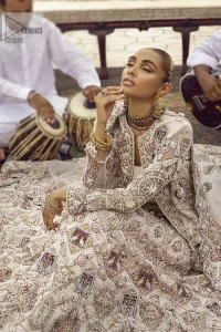 This vibrant canvas is all your brides need to cheer in at your special Nikah moments. A beige white blouse has a V shape neckline and full sleeves embellished with golden and silver embroidery. It is further intensified with special tills, dabka, kora, Kundan and the magic of zardozi to make your day outstanding and more funable. It is paired up with embroidered scalloped lehenga to fulfil the dreamy fairy look of the bride. Complete this article with a scalloped dupatta in the same colour with a four-sided embellished border and sequins sprayed all over to cheer up.