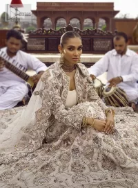 This vibrant canvas is all your brides need to cheer in at your special Nikah moments. A beige white blouse has a V shape neckline and full sleeves embellished with golden and silver embroidery. It is further intensified with special tills, dabka, kora, Kundan and the magic of zardozi to make your day outstanding and more funable. It is paired up with embroidered scalloped lehenga to fulfil the dreamy fairy look of the bride. Complete this article with a scalloped dupatta in the same colour with a four-sided embellished border and sequins sprayed all over to cheer up.