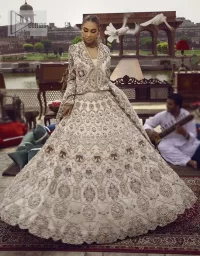 This vibrant canvas is all your brides need to cheer in at your special Nikah moments. A beige white blouse has a V shape neckline and full sleeves embellished with golden and silver embroidery. It is further intensified with special tills, dabka, kora, Kundan and the magic of zardozi to make your day outstanding and more funable. It is paired up with embroidered scalloped lehenga to fulfil the dreamy fairy look of the bride. Complete this article with a scalloped dupatta in the same colour with a four-sided embellished border and sequins sprayed all over to cheer up.