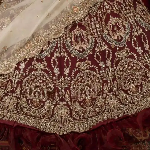 Take your style up a few notches in this elegant reception piece. A pure organza maroon fluffy lehnga is beautifully