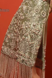 Celebrate your party events with DeemasFashion. An olive green shirt in tissue fabric, hand embellished with dabka, nakshi, cut dana, Resham, Swarovski, Mukesh, sequin and Kundan. A heavily embellished bodice featuring floral patterns all over to make your party event marvellous and shiny. The following heavy shirt is enhanced with V shape neckline along the sleeveless style. The bottom of the shirt has handsome fringes to give you a charming and splendid look.