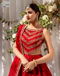 Master of artists who are the secret keepers of the canvas made the perfect shade of red for you to wear at your reception. A pure organza canvas of blouse, dipped in the richest shade of red, is adorned with dabka, sequins, tilla, kora and the magic of Resham. The following blouse is further magnified with golden embroidery with the highest attention to detail. The Round shape neckline of the blouse gives so romantic look when comes with a sleeveless style. It is paired u with flared and fluffy lehenga in silk whose bottom is heavily embellished. Complete this outfit with an organza dupatta framed with four-sided borders to be the star of the show.