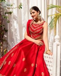 Master of artists who are the secret keepers of the canvas made the perfect shade of red for you to wear at your reception. A pure organza canvas of blouse, dipped in the richest shade of red, is adorned with dabka, sequins, tilla, kora and the magic of Resham. The following blouse is further magnified with golden embroidery with the highest attention to detail. The Round shape neckline of the blouse gives so romantic look when comes with a sleeveless style. It is paired u with flared and fluffy lehenga in silk whose bottom is heavily embellished. Complete this outfit with an organza dupatta framed with four-sided borders to be the star of the show.