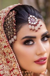 Shine bright in the sparkling ensemble from DeemasFashion. Introducing this reception outfit which begins with a rust pishwas.  This front en pishwas dipped in the richest shade of rust and is ornamented with golden embroidery which is further intensified with tilla, dabka, sequins and the real magic of zardozi. The strap neckline of the pishwas gives a unique aesthetic sense when comes with full sleeves. It is coordinated with an ivory lehenga whose border is embellished with golden embroidery. Finish this article with a dupatta framed with a four-sided embroidered border and sequin sprayed all over.