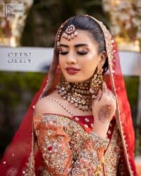 Shine bright in the sparkling ensemble from DeemasFashion. Introducing this reception outfit which begins with a rust pishwas.  This front en pishwas dipped in the richest shade of rust and is ornamented with golden embroidery which is further intensified with tilla, dabka, sequins and the real magic of zardozi. The strap neckline of the pishwas gives a unique aesthetic sense when comes with full sleeves. It is coordinated with an ivory lehenga whose border is embellished with golden embroidery. Finish this article with a dupatta framed with a four-sided embroidered border and sequin sprayed all over.