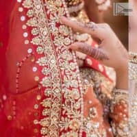 Shine bright in the sparkling ensemble from DeemasFashion. Introducing this reception outfit which begins with a rust pishwas.  This front en pishwas dipped in the richest shade of rust and is ornamented with golden embroidery which is further intensified with tilla, dabka, sequins and the real magic of zardozi. The strap neckline of the pishwas gives a unique aesthetic sense when comes with full sleeves. It is coordinated with an ivory lehenga whose border is embellished with golden embroidery. Finish this article with a dupatta framed with a four-sided embroidered border and sequin sprayed all over.