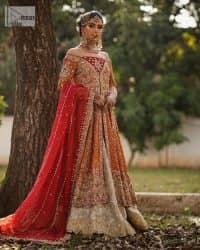 Shine bright in the sparkling ensemble from DeemasFashion. Introducing this reception outfit which begins with a rust pishwas.  This front en pishwas dipped in the richest shade of rust and is ornamented with golden embroidery which is further intensified with tilla, dabka, sequins and the real magic of zardozi. The strap neckline of the pishwas gives a unique aesthetic sense when comes with full sleeves. It is coordinated with an ivory lehenga whose border is embellished with golden embroidery. Finish this article with a dupatta framed with a four-sided embroidered border and sequin sprayed all over.