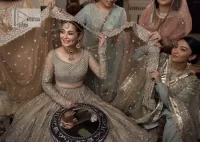 Regal and Charismatic - This is all the outfit is about! A desirable beige lehenga and choli are entirely heavily embroidered with silver colour and embellished with sequins, tilla, naqshi, Zardozi and Dabka. Its stunning heavily embellished blouse has full sleeves and the blouse consists of V shape neckline. It is coordinated with flared lehenga which is adorned with beautiful embroidery to make this walima wear balance. Finish this with a dupatta that has silver sequin and tiny floral motifs all over. The dupatta is framed with a four-sided embellished border to make this masterpiece unique and attractive.