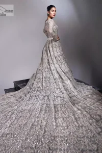 The trend of the back trains is still going strong as nikah wear - Here is the perfect one! This beautiful silver maxi is heavily embellished with silver embroidery. The gorgeous work of pearls, dabka, kora, Kundan and silver stones enhance the overall glamour of this maxi. The extraordinary design of the jewel neckline is completely embellished with silver stones and pearls embroidery combinations. The silver stones touch-up increases the looks of the beautiful gown with long tails that gives everlasting impact and at the bottom is the double flare. The full sleeves of the maxi are the lavishing style that any bride can wear on her big day.