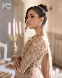 Make your Qabool Hai moment more memorable with this outfit by DeemasFashion. A dreamy statement of this dress proffers a soft pink hue with glamorous silver and golden embroidery.  It is further enhanced with tilla, dabka, kora, Kundan and the real magic of zardozi. V neckline enhances the overall glamour of this masterpiece. Intricate designs and fine details on the sleeves give a perfect finishing look to this maxi. The maxi is layered over a meticulously handcrafted lehnga which is bold enough to stand out in the crowd. Finish this article with a dupatta which is ornamented with four-sided borders and sequins sprayed all over which is a unique piece for your Nikah look.