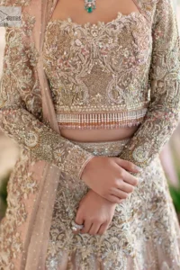 Trendy embroidery on a classic base – A perfect combination for your Nikah! DeemasFashion presents the tea rose article which is laboriously embellished with light golden embroidery which is further enhanced with tilla, dabka, kora, Kundan and beautiful details of Zardozi. The neckline is decorated with handsome embroidery. Further, the full sleeves of the blouse are unique in style and have a classy look and perfect choice for a bride. It is paired with flared lehenga which is heavily ornamented with embroidery to make your day memorable. Complete this article with a dupatta, framed with four-sided borders and sequins spray all over which is giving a charming finishing look to the dress.
