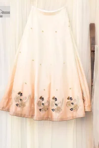 The fusion of this softest canvas decorated with vibrant contrasts is all you need to stun at any party! The embellished ivory article is the season’s most irresistible trend, the new-age lehenga blouse. The impeccably tailored choli has delicate multiple colour embroidery which intensifies with tilla, dabka, kora, Kundan and magic of Zardozi. The round neckline of the blouse is a beautifully crafted ensemble when combined with sleeveless style. The following blouse is paired with a double-tone can-can lehenga which is ornamented with embroidery on the border making it a perfect choice to pair with this masterpiece.