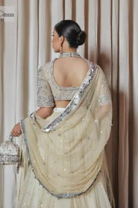 The perfect balance of simplicity and flamboyance is the essence of the beautiful Walima outfit. The blouse in off-white colour is beautifully embellished with Dabka, Tilla, Zardozi and delicate yet intricate crystal work. The beautiful classy artistic half sleeves design maintains the charm of this blouse. The beautiful outfit is epitome of beauty by its high neckline . It is paired up with flared lehenga in the same colour, framed with a sequins sprayed all over. Further, beautiful silver embroidery on the four sided border of the dupatta will enhance the overall magnificent look.
