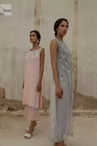 Balancing outfit lovers here’s your style treat! The handsome and charming steel grey attire is an epitome of elegance and royalty that gives you a head-turning appearance on the party occasion. The front open gown is laden with silver embroidery that is further enhanced with tilla, dabka, kora, Kundan and luxuries of crystals. The round neckline of this gown is emblazoned with luxury designs and embroidery. In addition to this, the sleeveless style makes this article a masterpiece. Paired up with straight trousers to balance the look of this exquisite article.