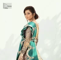 Celebrate your party with a bang and steal everyone's heart. The beautiful blouse in teal green shade comes in organza fabric. The boat shape neckline and full sleeves of this organza blouse are emblazoned with luxury details and intricate designs. Graceful golden embroidery that enhances with tilla, dabka, kora, Kundan, Zardozi and crystals to give a perfect finishing look to the blouse. It is organized with a back train lehenga which is heavily adorned with embroidery to make this masterpiece super aesthetic. Finish this outfit with a scalloped dupatta having four-sided embellished borders for a fine finishing look.