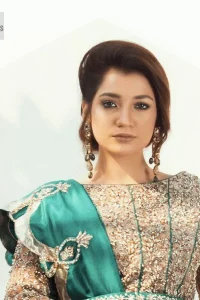 Celebrate your party with a bang and steal everyone's heart. The beautiful blouse in teal green shade comes in organza fabric. The boat shape neckline and full sleeves of this organza blouse are emblazoned with luxury details and intricate designs. Graceful golden embroidery that enhances with tilla, dabka, kora, Kundan, Zardozi and crystals to give a perfect finishing look to the blouse. It is organized with a back train lehenga which is heavily adorned with embroidery to make this masterpiece super aesthetic. Finish this outfit with a scalloped dupatta having four-sided embellished borders for a fine finishing look.