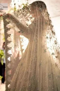 The magic reflects in every piece of this nikah wear. DeemasFashion presents a stunning outfit in an aqua-blue colour. A heavenly designed aqua blue maxi on an organza base serves as a canvas for spellbinding embellishments of gold, tilla, dabka, kora, Kundan and sequins. It is highlighted with silver embroidery to gain the spotlight of the show. The jewel neckline and full sleeves are rendered with beautiful floral patterns and embroidered borders. It is organized with a lehenga in the same colour, adorned with beautiful embroidery giving the perfect final touch. Complete this outfit with a dupatta in the same colour. This dupatta is adorned with floral motifs and silverwork. The embellished borders of this delicate net dupatta make this article your foremost priority.