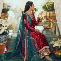 Dreamy details that scream crimson. The day outfits you need to shine your light. DeemasFashion presents this party wear which includes a long shirt, sharara and dupatta. The deep crimson shirt gives that air of regality with its stunning work with hints of tilla, dabka, kora, and Kundan scattered with champagne-mixed stones to balance the tones. The following long silhouette velvet shirt features zari and zardozi embroidery details on the embellished neckline. Further, the full sleeves are also decorated with floral motifs. It is systemized with sharara in the same colour to balance the royal look. Finish this article with a dupatta in green colour which is adorned with tiny floral motifs all over to brighten the day.