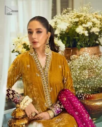 This mustard ensemble features zari and tilla details creating the perfect magical look for the season! The stunning long shirt in an alluring mustard shade comes in velvet fabric. The V-neckline of this shirt is emblazoned with embroidery and hand-crafted embellishments. Motifs, tilla, and threads give a perfect finishing look to the shirt. It is enhanced with multiple colours embroidered patches at the bottom to stole everyone's heart. It is paired with scalloped burgundy trousers to balance the overall look of this party wear. Complete this with a dupatta having tiny floral motifs and sequins sprayed all over.