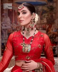Statement suiting in red. This red blouse comes with a lehenga and dupatta in premium fabric quality. The blouse is beautifully decorated with fine embroidery work accompanied by iridescent sequins, tilla, dabka, kora and Zardozi. Furthermore, beautiful artistry on the neckline is highlighted with golden embroidery accompanied by cutwork counting more to the elegance of this luxurious attire. It is organized with a flared lehenga in the same colour. This embroidered lehenga comes is very neatly stitched and decorated with lavish embroidery and minimal floral motifs making this dreamy attire look heavenly and your ultimate priority. Complete this reception wear with a dupatta framed with four-sided embellished borders that is your favourite statement on your big day.