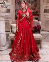 Statement suiting in red. This red blouse comes with a lehenga and dupatta in premium fabric quality. The blouse is beautifully decorated with fine embroidery work accompanied by iridescent sequins, tilla, dabka, kora and Zardozi. Furthermore, beautiful artistry on the neckline is highlighted with golden embroidery accompanied by cutwork counting more to the elegance of this luxurious attire. It is organized with a flared lehenga in the same colour. This embroidered lehenga comes is very neatly stitched and decorated with lavish embroidery and minimal floral motifs making this dreamy attire look heavenly and your ultimate priority. Complete this reception wear with a dupatta framed with four-sided embellished borders that is your favourite statement on your big day.