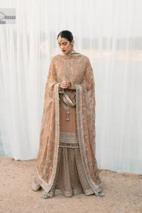This ensemble is an absolute vibe with a tempting design on a beautiful base!  This beautiful party wear is designed in soft brown colour which is modern yet classy. The short shirt is adorned with silver embroidery which is further enhanced with tilla, dabka, kora, Kundan and the details of Zardozi. The beautiful tussles also hang on the bottom of the embellished neckline to make it a perfect choice for everyone Further, the floral patterns on full sleeves also intensify the charms of the outfit. It is coordinated with a sharara to balance the overall look. Complete this with a dupatta embellished with a four-sided border and floral jaal all over.