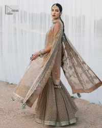 This ensemble is an absolute vibe with a tempting design on a beautiful base!  This beautiful party wear is designed in soft brown colour which is modern yet classy. The short shirt is adorned with silver embroidery which is further enhanced with tilla, dabka, kora, Kundan and the details of Zardozi. The beautiful tussles also hang on the bottom of the embellished neckline to make it a perfect choice for everyone Further, the floral patterns on full sleeves also intensify the charms of the outfit. It is coordinated with a sharara to balance the overall look. Complete this with a dupatta embellished with a four-sided border and floral jaal all over.