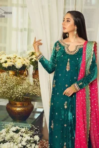 Brighten up your day with this beautiful ensemble. This long shirt style in a teal green colour is a perfect outfit that gives you a royal look on the festive occasion. The embroidered neckline and full sleeves make this outfit an epitome of beauty. Further, Embroidery work which enhances with tilla, dabka, kora, Kundan and lavish designs makes this outfit your priority for the day. It is paired with plum trousers which have finished edges to balance the overall look of the day. Complete this party wear with a dupatta in pink colour sparkling sequins spray all over. 