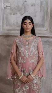 Make a style statement in this beautiful tea-pink canvas. The heavy shirt comes in a tea-pink colour and is gracefully emblazoned with silver embroidery. Hand-crafted details of sequins, tilla, dabka, kora and Zardozi give a glamorous touch to this beautiful party wear. Further, the crystalline hanging also makes this masterpiece unique and gives you a royal look. The round neckline also adds beauty to the outfit. It is paired up with trousers to balance the overall outfit.
