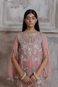 Make a style statement in this beautiful tea-pink canvas. The heavy shirt comes in a tea-pink colour and is gracefully emblazoned with silver embroidery. Hand-crafted details of sequins, tilla, dabka, kora and Zardozi give a glamorous touch to this beautiful party wear. Further, the crystalline hanging also makes this masterpiece unique and gives you a royal look. The round neckline also adds beauty to the outfit. It is paired up with trousers to balance the overall outfit.