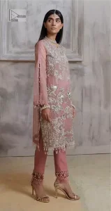 Make a style statement in this beautiful tea-pink canvas. The heavy shirt comes in a tea-pink colour and is gracefully emblazoned with silver embroidery. Hand-crafted details of sequins, tilla, dabka, kora and Zardozi give a glamorous touch to this beautiful party wear. Further, the crystalline hanging also makes this masterpiece unique and gives you a royal look. The round neckline also adds beauty to the outfit. It is paired up with trousers to balance the overall outfit.