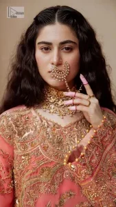 It's an aesthetic kinda mood. The long shirt in the wondrous peach colour is composed of ethnic handworked details and gleaming embellishments rendered artistically on a Jamawar canvas. The long shirt is layered with embroidered details with an enhanced V neckline and borders. The beautiful shirt is prominent with tilla, dabka, kora, Kundan and Zardozi in gold colour. Further, the intricate floral patterns on full sleeves make this outfit crazier. Complementing the shirt with gharara with elaborated borders depicts a perfect contemporary vibe.