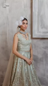 Get this ever-trending floral walima outfit.  Keep it romantic and fantastic with the DeemasFashion latest articles! The soft green blouse is gracefully embellished with silver and gold embroidery that gives you a head-turning appearance on the wedding day. The blouse is enhanced with tilla, dabka, kora, Kundan, and crystals. The off-shoulder neckline of the blouse makes this stunning attire an epitome of royalty and grace. It is paired with a flared lehenga that is also adorned with embroidery to make your day fantastic. Complete this article with a dupatta framed with four-sided embellished borders and sequins sprayed all over.