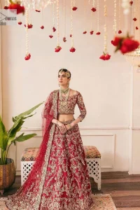The beauty of this ensemble is mirrored in the romantic colour palette! The blouse is in a dark red shade and is fully decorated with intricate designs and fine details of goldwork. Lavish embroidery, tilla,dabka, kora, Kundan, gold, and zari work make this reception outfit a charismatic masterpiece. The boat shape neckline on a scalloped blouse gives the gorgeous Bride a head-turning look. In addition to this, the three-quarter sleeves for a more upscale appearance and feel. It is systemized with a lehenga in the same colour adorned with heavy floral patterns that are essential for your dreamy look. Complete this romantic look with a dupatta framed with four-sided embellished borders and sequins sprayed all over. Still, thinking? This is a no-brainer. Get your hands on this one ASAP before it sells out!