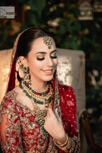 Classic deep red canvas with a bold twist of the pattern!  Bridal choli in the deep red shade is a beautiful attire to wear on the big day to have an elegant and classy look. This beautiful choli is heavily embellished with crystals, pearls, dabka,tilla, kora, Kundan, stones, and Zardozi giving a magnificent touch to the lehenga choli. The round neckline of the attractive blouse makes an outfit look more sophisticated. Further, the beautiful floral patterns on three-quarter sleeves make this outfit a must-have for your day. It is paired with a heavily embellished lehenga and is a stylish choice for the gorgeous Bride. Complete this romantic article with a dupatta framed with four-sided embellished borders and sequins sprayed all over.