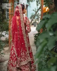 Classic deep red canvas with a bold twist of the pattern!  Bridal choli in the deep red shade is a beautiful attire to wear on the big day to have an elegant and classy look. This beautiful choli is heavily embellished with crystals, pearls, dabka,tilla, kora, Kundan, stones, and Zardozi giving a magnificent touch to the lehenga choli. The round neckline of the attractive blouse makes an outfit look more sophisticated. Further, the beautiful floral patterns on three-quarter sleeves make this outfit a must-have for your day. It is paired with a heavily embellished lehenga and is a stylish choice for the gorgeous Bride. Complete this romantic article with a dupatta framed with four-sided embellished borders and sequins sprayed all over.