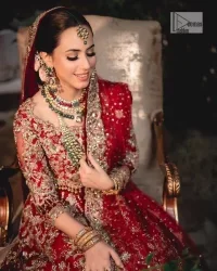 Classic deep red canvas with a bold twist of the pattern!  Bridal choli in the deep red shade is a beautiful attire to wear on the big day to have an elegant and classy look. This beautiful choli is heavily embellished with crystals, pearls, dabka,tilla, kora, Kundan, stones, and Zardozi giving a magnificent touch to the lehenga choli. The round neckline of the attractive blouse makes an outfit look more sophisticated. Further, the beautiful floral patterns on three-quarter sleeves make this outfit a must-have for your day. It is paired with a heavily embellished lehenga and is a stylish choice for the gorgeous Bride. Complete this romantic article with a dupatta framed with four-sided embellished borders and sequins sprayed all over.