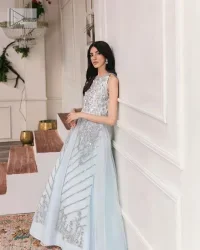 Shine and sparkle in this ice-blue nikah outfit! A mesmerizing long shirt stuns in a beautifully handcrafted silver embroidery enshrined with tilla,dabka, kora, Kundan, Zardozi, stones and the real magic of crystals. The jewel neckline has detailed intricate floral patterns. The sleeveless style of this ice blue front open shirt is the true essence of DeemasFashion. It is organized with a plain lehenga in the same colour to complete your stylish appearance.