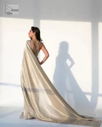 It's an aesthetic kinda mood. A silver blouse hand embellished with dabka, naqshi, cut dana, Resham, tilla, kora, sequin and Kundan. A heavily embellished blouse featuring floral patterns encompassing a breathtaking keyhole and vertical embellishments along the strips of the back flare. The V shape neckline of the blouse looks divine when comes with a sleeveless style. It is paired with a scalloped saree with an embellished border and the pallu is decorated with silver embroidery to make this Nikah outfit lovely and charming. 