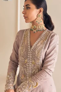 Feel the magic of the party in this splendid article! The ideal front open gown in tea rose colour is heavily hand embellished with floral branches and botanical motifs. It has an embroidered border on the front and back. The V shape neckline is adorned with silver and golden embroidery. It is further prominent with tilla,dabka, kora, Kundan, crystals, stones and the intricate detailing of Zardozi to make this masterpiece lovely and charming. Further, the full sleeves are decorated with tiny floral motifs and sequins spray. It is paired with trousers that complete the party wear look.